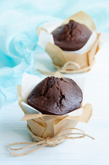 Chocolate muffins in wrapping on wooden table