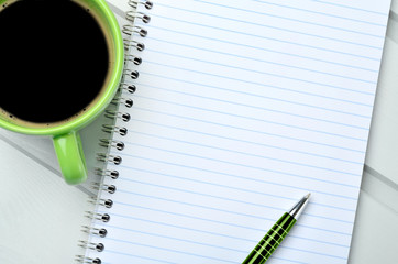 Empty notebook with cup of coffee on table - obrazy, fototapety, plakaty