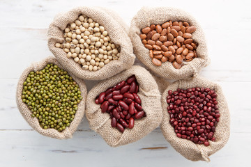 Assortment of beans and lentils in hemp sack on wooden backgroun