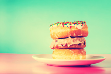 Stack of assorted donuts on blue and pink background