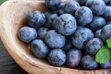 Heidelbeeren close-up in Holzschale und Minzblatt