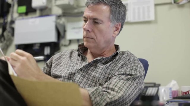 A seasoned IT administrator in his office looking over some paperwork and making notes.