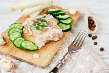 
Ukrainian and Russian national cuisine , the dish is called brawn , boiled pork and turkey in jelly of bouillon with fresh cucumber , salt and spices on a wooden background