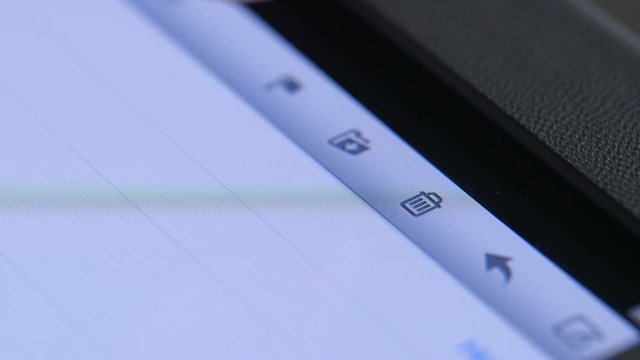Unwanted emails and other data being deleted from a digital tablet pc by a woman touching the trashcan icon on the touchscreen.