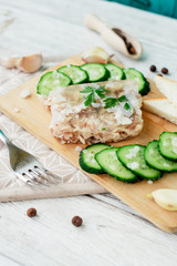 
Ukrainian and Russian national cuisine , the dish is called brawn , boiled pork and turkey in jelly of bouillon with fresh cucumber , salt and spices on a wooden background