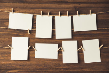 empty photo frames hanging with clothespins on wooden background