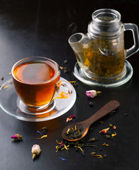 Cup of tea and teapot and assorted herbs with a spoon