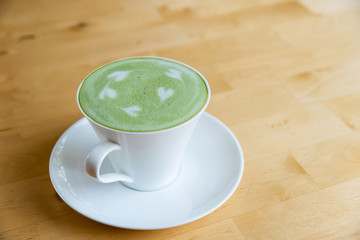 hot green tee latte in white cup on wooden table