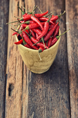 red peppers in a mug with wooden background, vintage style