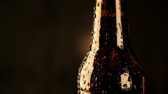 капли воды стекают по бутылке темного пива