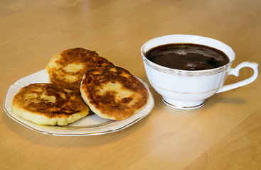 Сырники и чашка кофе эспрессо на деревянном столе, утро, завтрак.