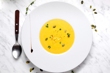 Pumpkin soup in a bowl with spoon on a murble