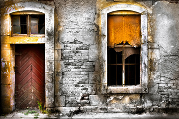 old damaged wall with barred window and a door