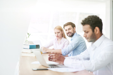 Fototapeta premium Cheerful three colleagues are working in cooperation