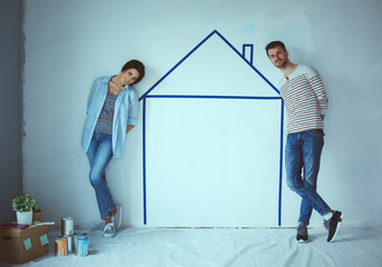 Couple standing in front of painted home on wall