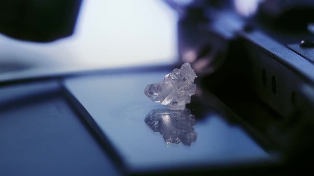 A piece of crystal meth being placed on a microscope slide