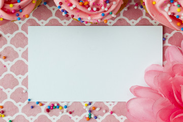 top view of an empty placard with flower and cupcakes.