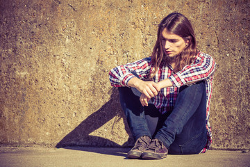 Man long haired sitting alone sad on grunge wall