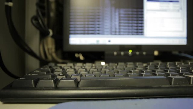 Computer code scrolling on a monitor with focus on keyboard.