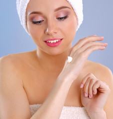 Young woman  putting cream on her hand Isolated on gray background