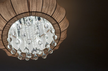 The chandelier is made of fabric with crystal pendants. A lit chandelier, bedroom interior. 