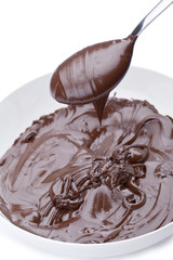 Fototapeta premium spoon full of melted chocolate over a bowl of melted chocolate