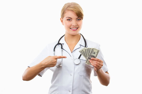 Woman doctor with stethoscope showing currencies dollar, corruption, bribe or paying for care concept