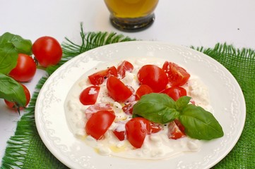 Salad from cherry tomatoes and cottage cheese with basil and olive oil