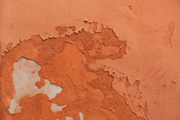 Old terracotta painted stucco wall with chipped paint. Backgroun