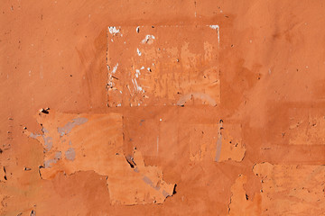 Traces of old announcements on terracotta wall. Background textu