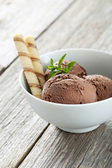 Sweet chocolate ice cream in bowl on grey wooden background