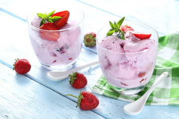 Ice cream in glasses with strawberries on blue wooden background