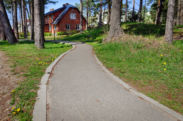 Asphalt road and red brick house among trees