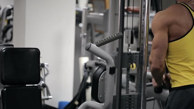 The man in the gym trains muscles of hands with a block circuit simulator