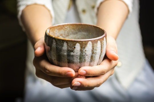A girl holding a Japanese tea cup