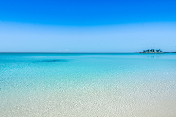 Fototapeta na wymiar Turquoise, crystal clear water and a small island in the background on Eleuthera (Bahamas).