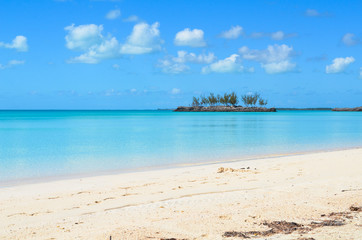 Turquoise, crystal clear water and a small island in the background on Eleuthera (Bahamas).