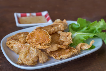 Deep fried crab meat rolls served on white plate on wooden table