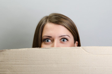 Banner sign woman peeking over edge of blank empty billboard with copy space for text. Beautiful woman