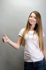 Portrait of a cheerful woman showing thumb up over gray background