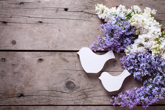 Flowers and decorative birda on wooden table.