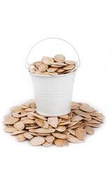 White bucket full of pumpkin seeds, stands on a heap pumpkin