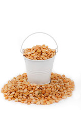 White bucket full of peas, stands on a heap peas
