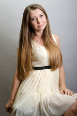 Beautiful woman wearing a dress sitting on a chair. Studio shot.