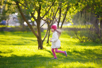 little girl running on green grass in the Park. child plays outdoor