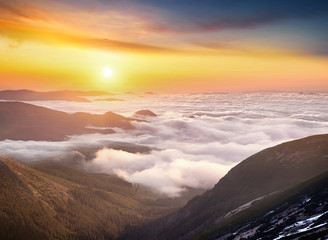 Mountain valley in the clouds during sunrise. Beautiful natural landscape in the summer time