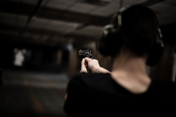 Man aiming revolver at target in indoor firing range or shooting range © guteksk7