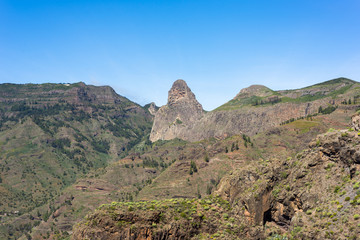 Fototapeta na wymiar The Roque de Agando, a huge volcanic plug 1250m high, and the Barranco de Benchijiguaon on La Gomera, Canary Islands. The Roque Agando is one of a group of volcanic plugs near the Garajonay Park