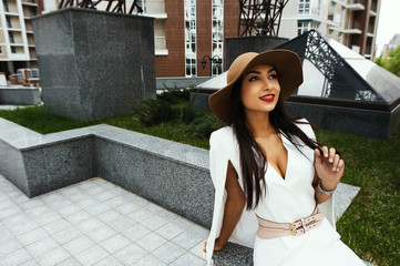 smiling raven haired indian lady posing in backyard of  high-rise building