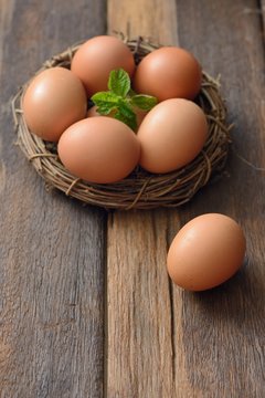 Brown Eggs and mint leaf in a nest on wooden table background